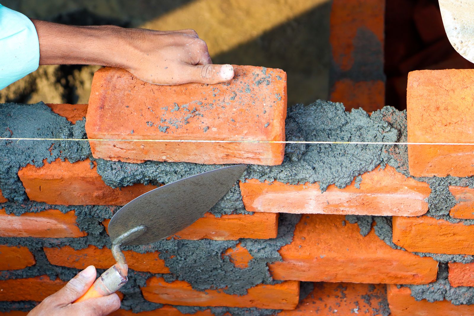 Mason laying brick with fresh mortar