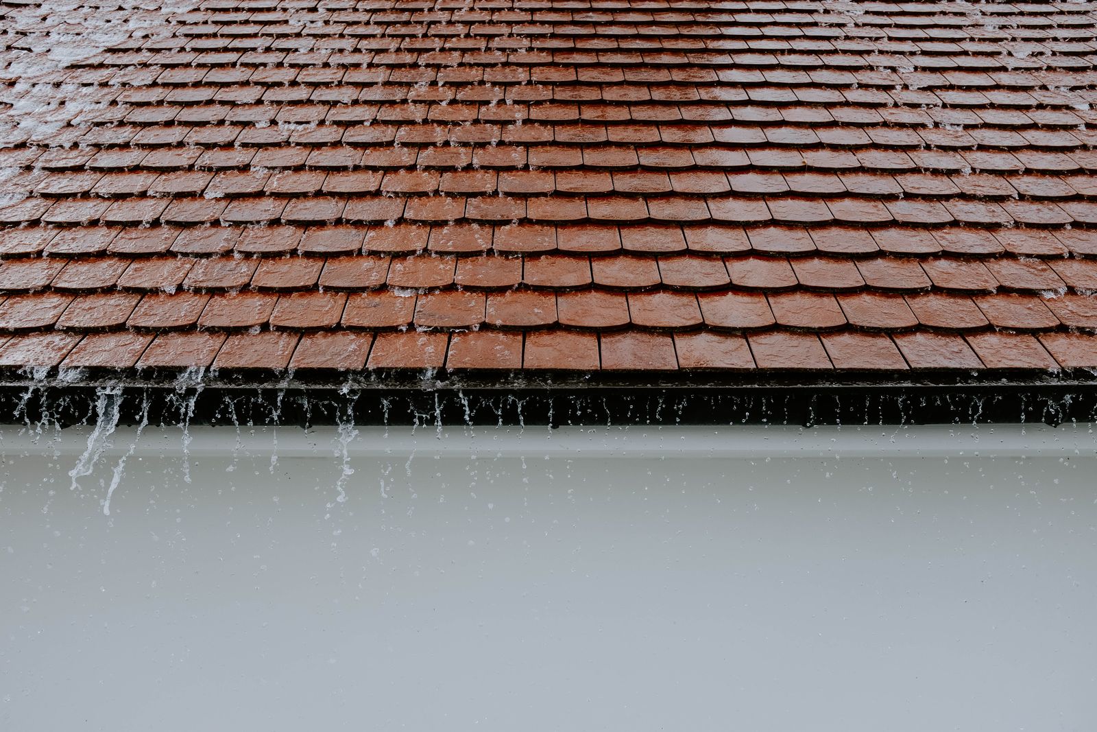 Rainwater cascading off a roof edge during a storm