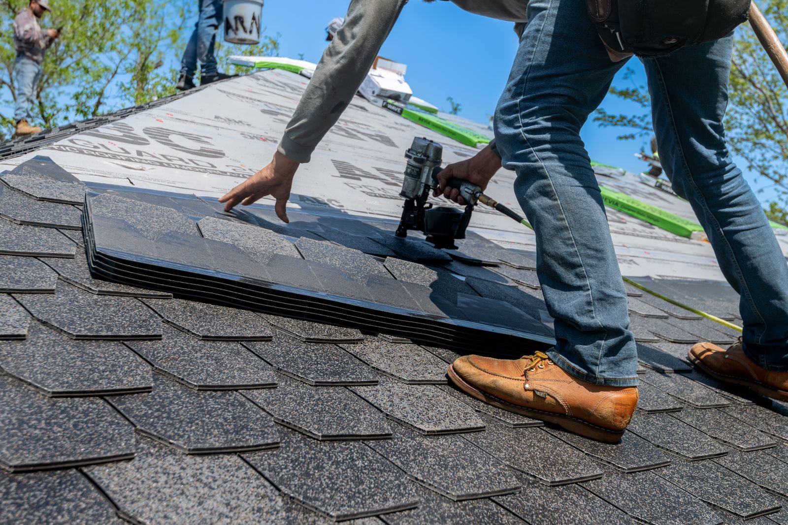 Roofer nailing shingles on a residential roof